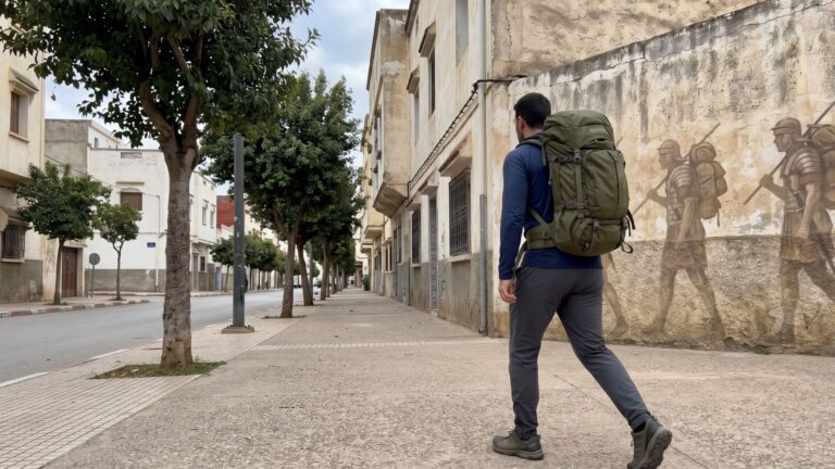Man rucking with weighted backpack on city sidewalk representing History of the Ruck March from ancient soldiers to modern fitness.